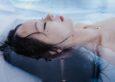 A person floating on their back in a pool with eyes closed, hair spreading in the water, illustrating the calm of an open pool float