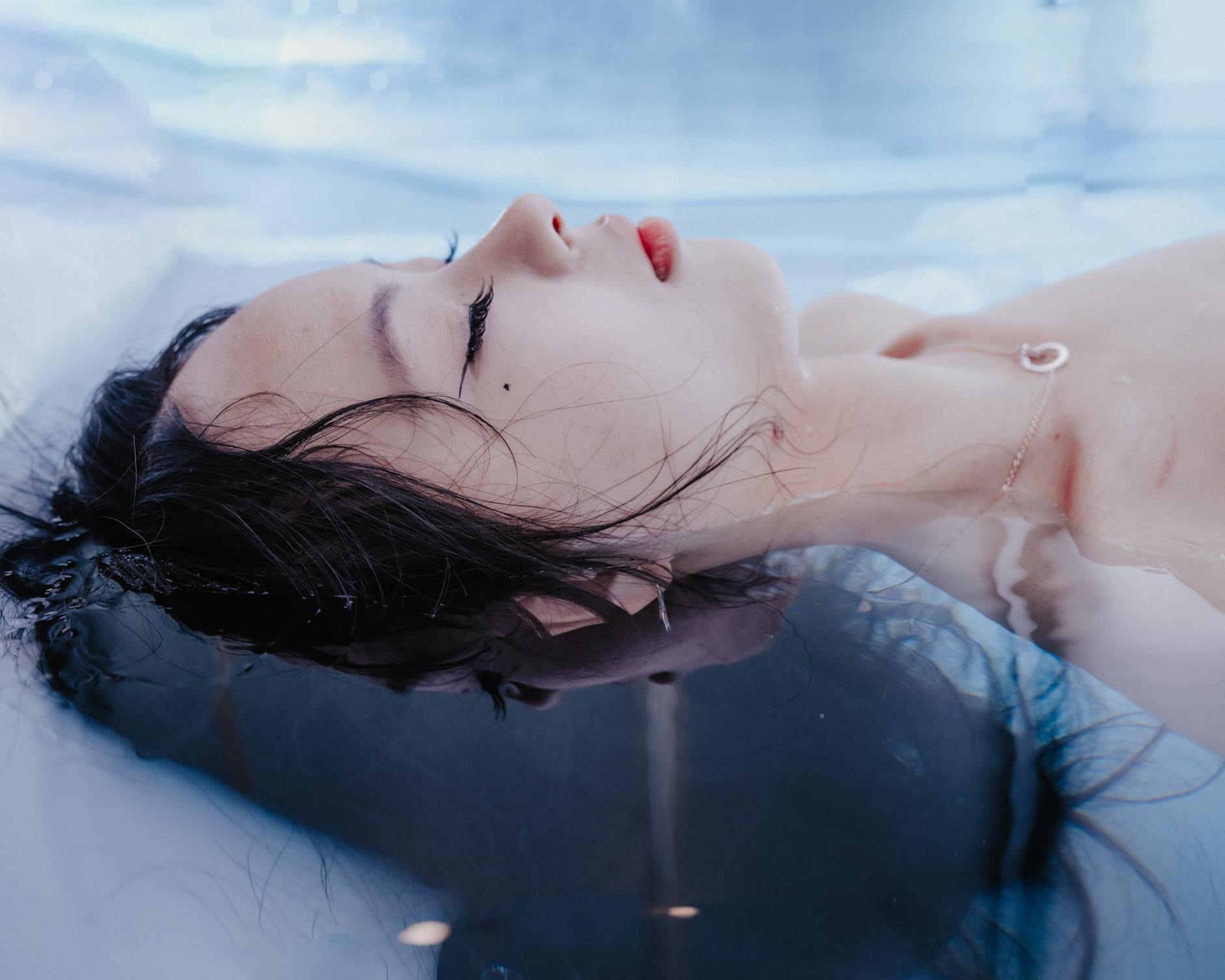 A person floating on their back in a pool with eyes closed, hair spreading in the water, illustrating the calm of an open pool float
